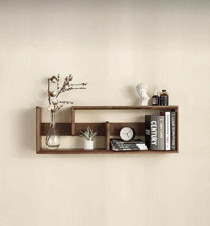 S-shape asymmetric walnut floating shelf with cotton blossom vase, succulent, books and clock on cream wall