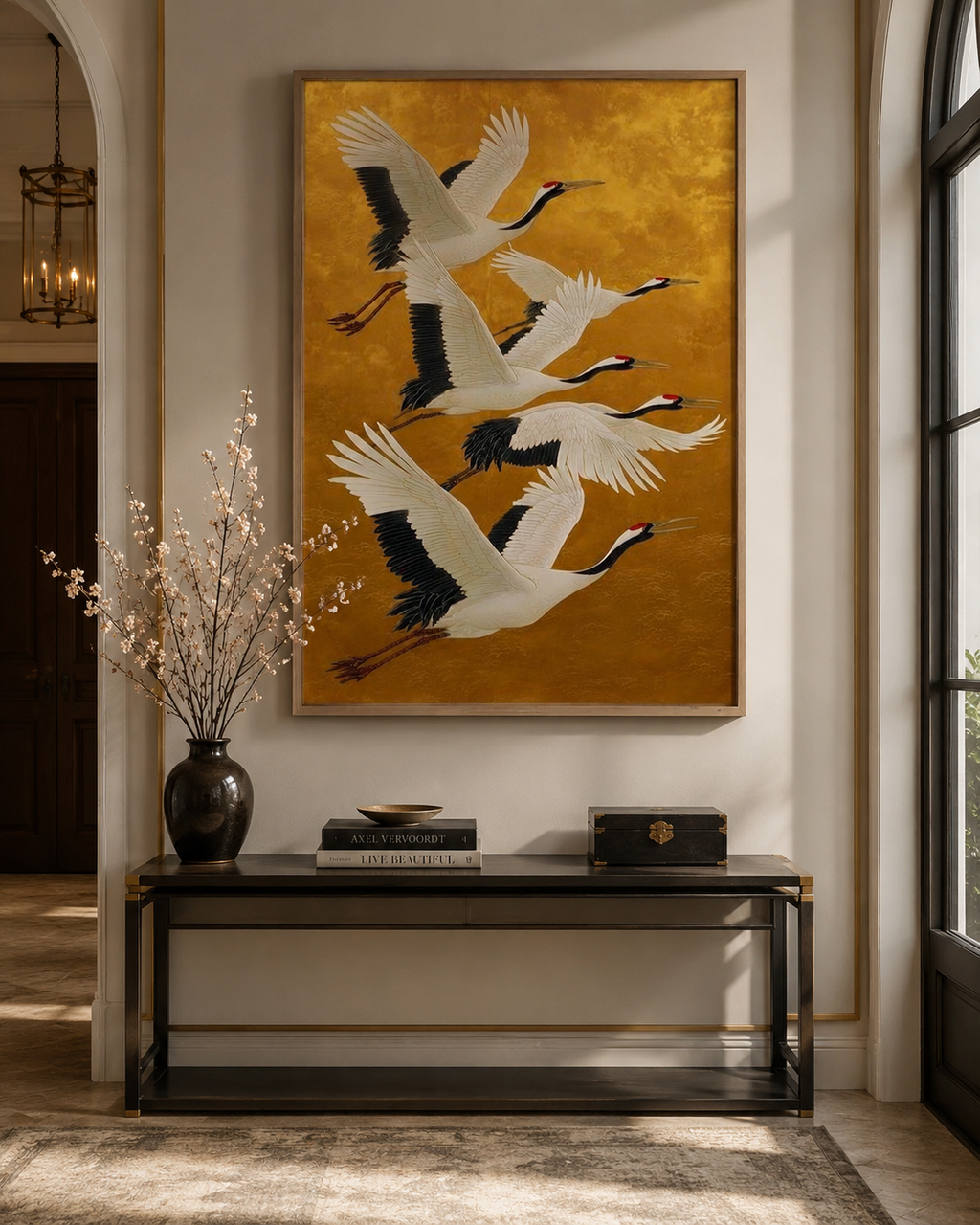 Golden cranes wall art above dark console table with black vase and cherry blossoms in grand entryway