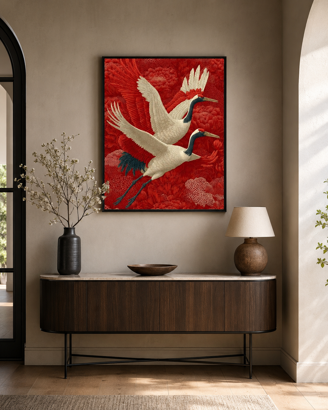 Red cranes wall art above curved dark wood console with black vase and round lamp in arched entryway