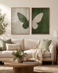 Green butterfly diptych set above cream boucle sofa with olive branches and round wood coffee table in warm living room