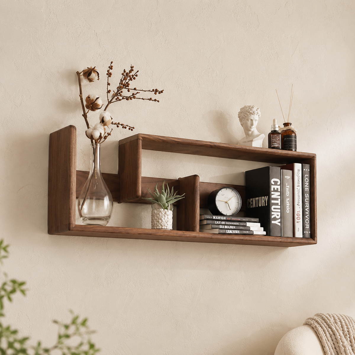 S-shape walnut display shelf close-up with cotton branch vase, Greek bust figurine and art books on cream wall